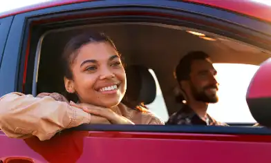 a person driving and a person looking out of the window of a red car